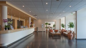 A spacious lobby with a reception desk, seating area, and potted plants.