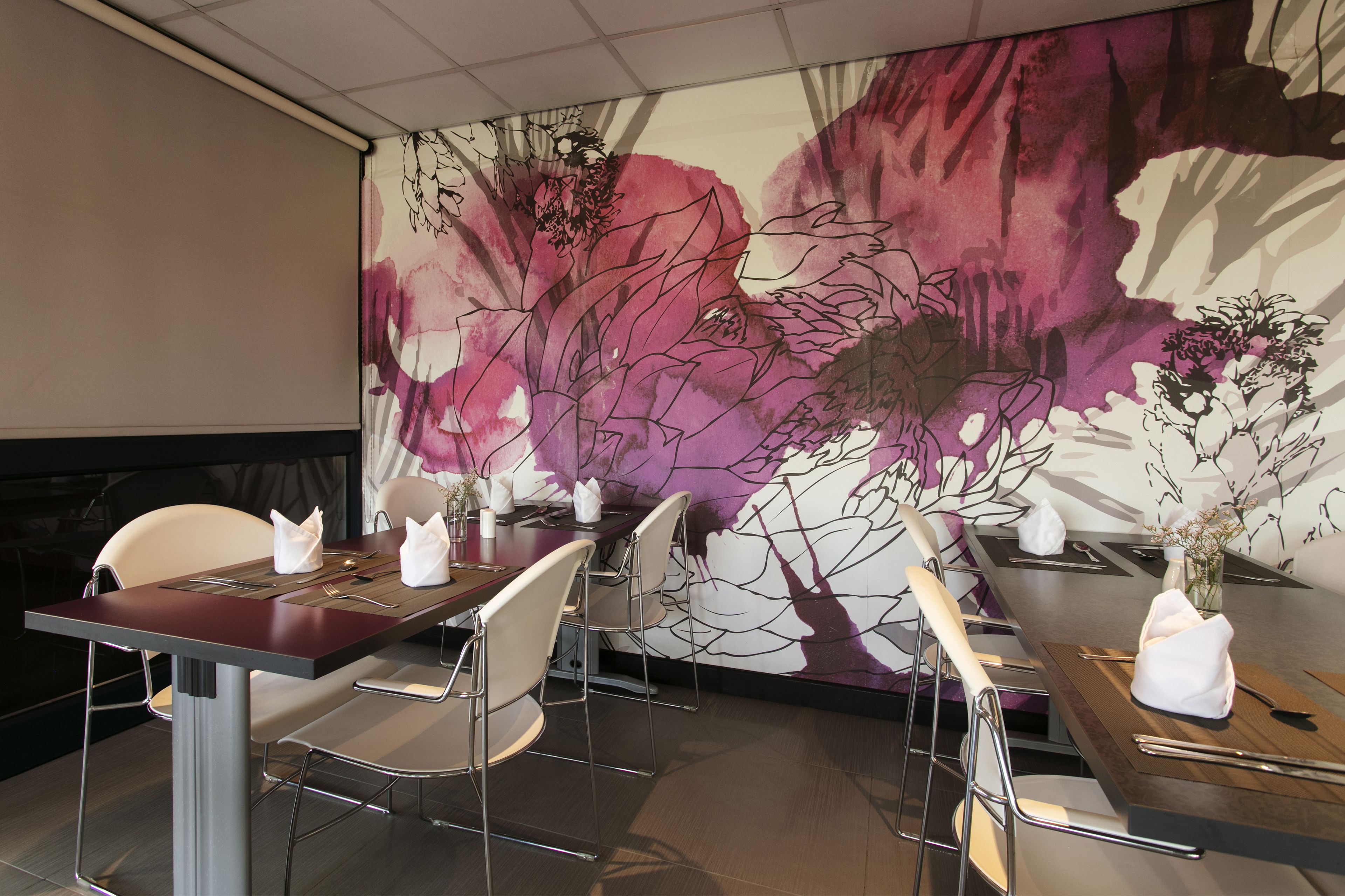 Un espace repas avec une longue table dressée pour six personnes, entourée de chaises modernes.