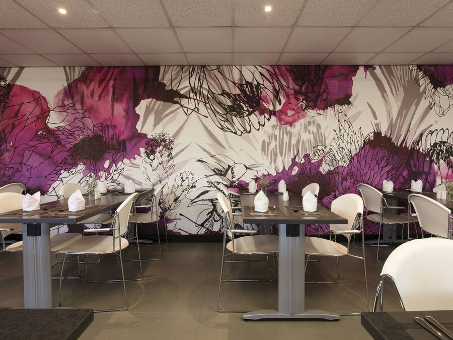 Un restaurant au décor moderne, avec une grande fresque florale sur le mur, un mobilier contemporain et un intérieur épuré et bien éclairé.