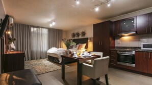 Een moderne hotelkamer met een bed, nachtkastje en een zithoek met een tafel en stoelen.