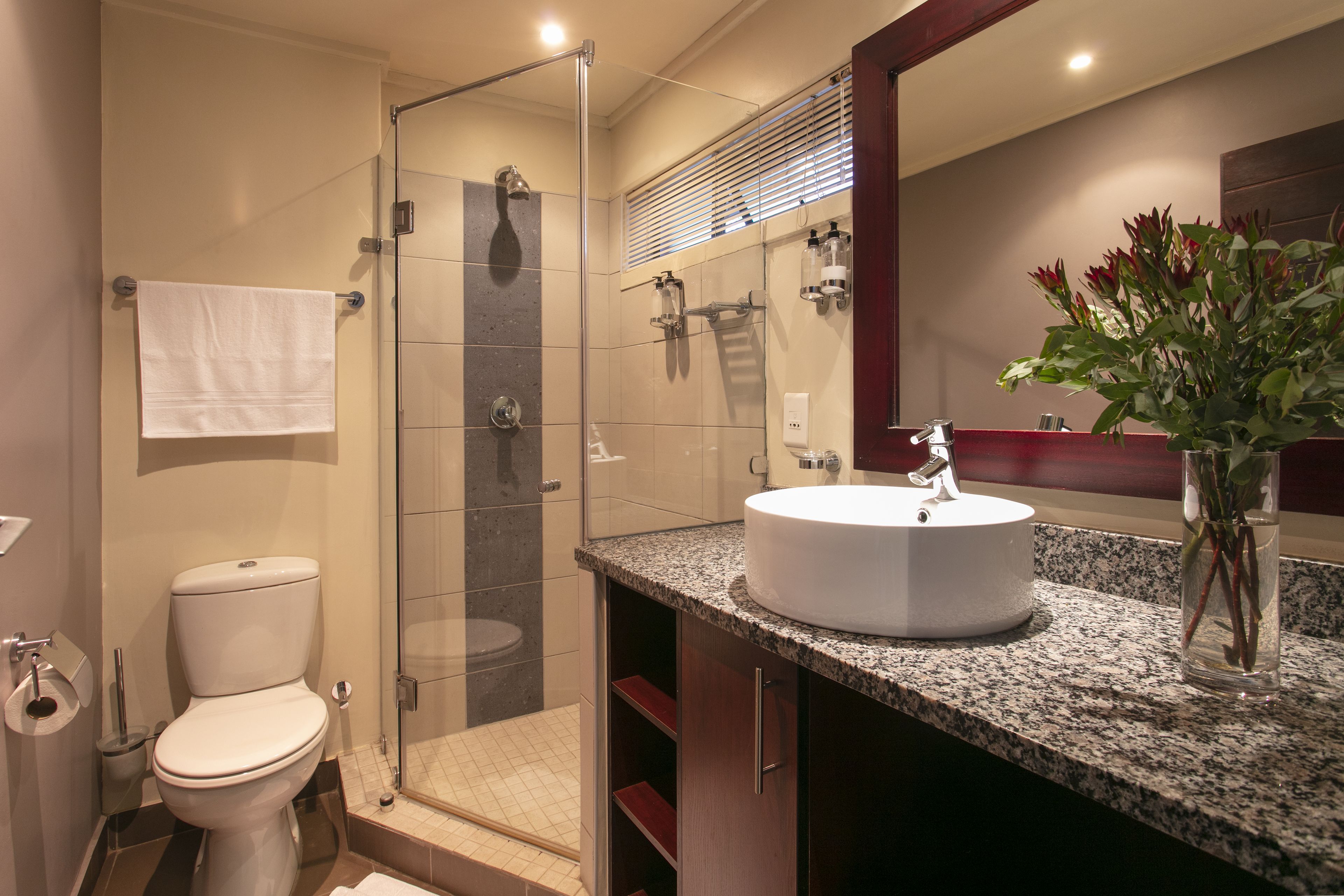A modern bathroom with a glass-enclosed shower, a white sink, and a mirror above it.
