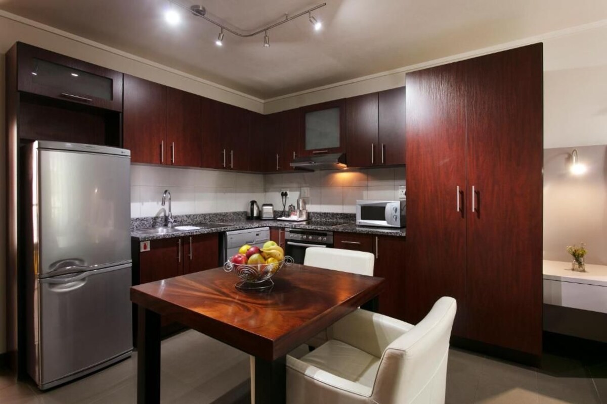 A modern kitchen with dark wood cabinets, stainless steel appliances, and a marble countertop.
