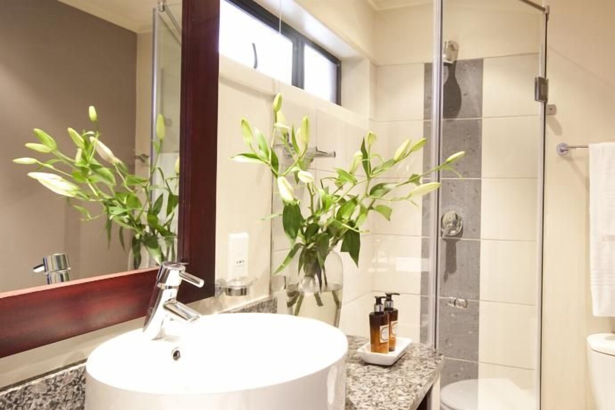 A bathroom with a round sink, a glass shower enclosure, and a towel rack.