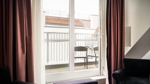 Une pièce avec une grande fenêtre, une chaise, un banc et un escalier.