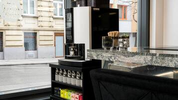 Una cafetera, tazas y una exhibición de granos de café en un ambiente moderno.