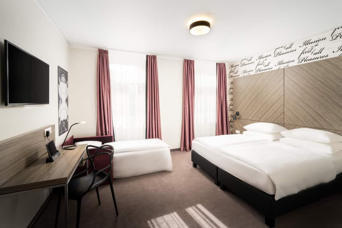 Une chambre d’hôtel avec un lit, un bureau, une chaise et un téléviseur.