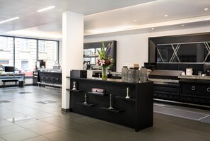 A modern kitchen with a black island, marble countertops, and a large window providing a view of the street. - elaya hotel vienna city west, Trademark by Wyndham (Vienna)