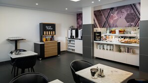 Un café moderne doté d’un comptoir, d’un espace salon et proposant une variété de plats et de boissons.