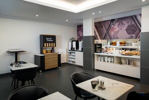 Un café moderne doté d’un comptoir, d’un espace salon et proposant une variété de plats et de boissons.