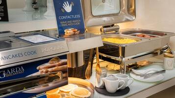 Un bufé de desayuno con servicio sin contacto, una plancha para panqueques y diversas opciones de comida.