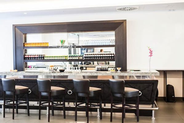 A bar area with a marble countertop, multiple bottles, and bar stools.