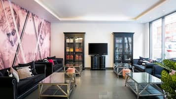 Uma sala de estar moderna com sofás pretos, mesas de centro de vidro e duas estantes repletas de livros.