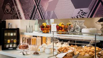 A buffet with various food items, including fruits, pastries, and condiments.