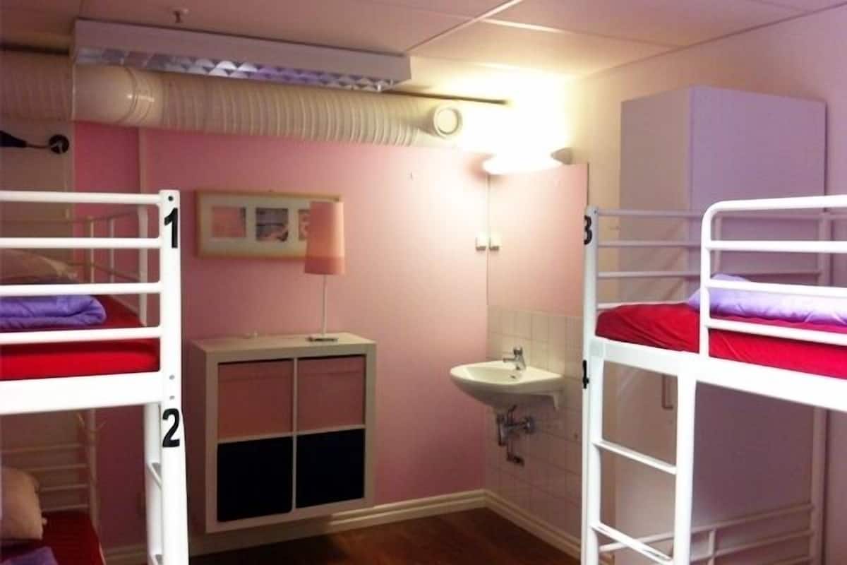 Une chambre avec deux lits superposés, un lavabo et un placard.