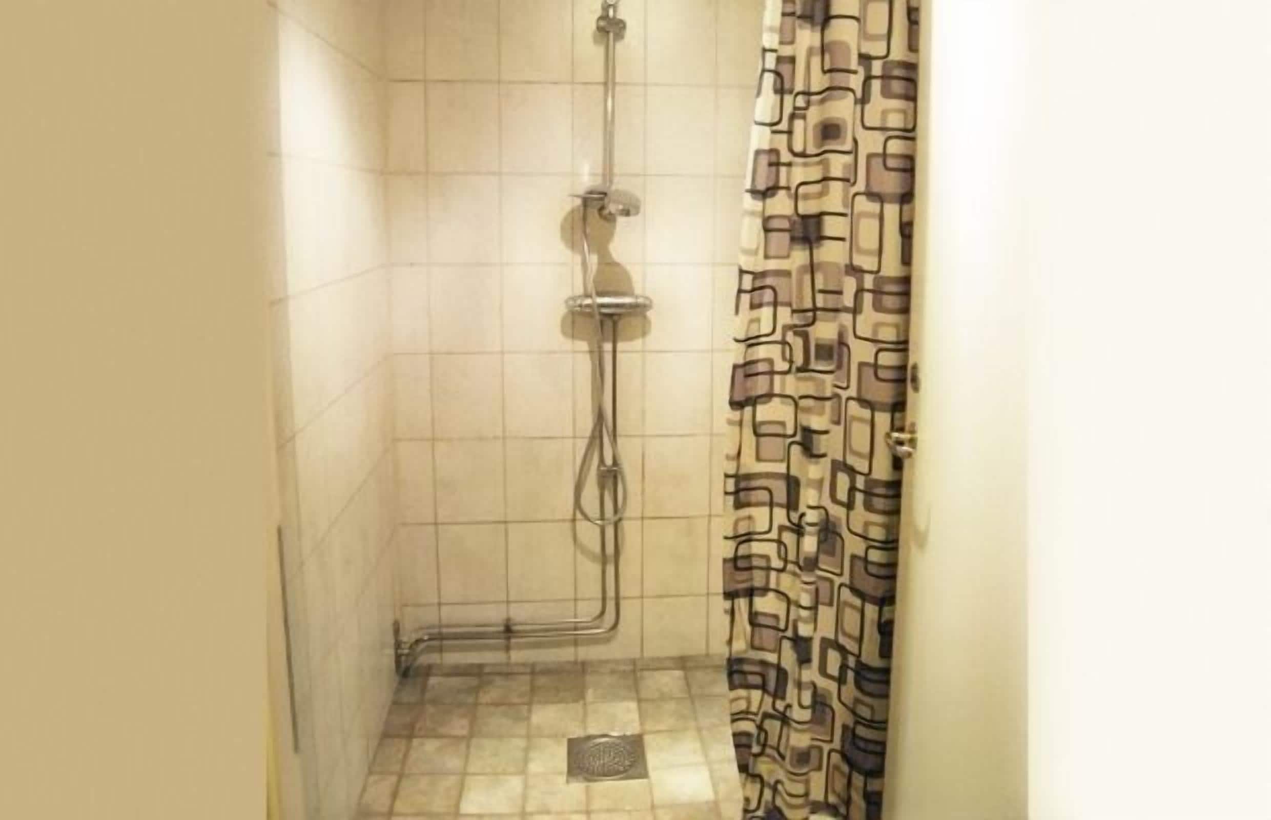 A small shower area with a tiled floor and a patterned shower curtain.