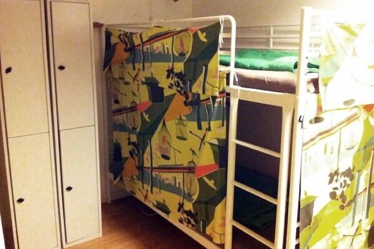 Un lit superposé avec une fresque colorée sur le mur, une armoire et une couverture verte sur le lit.