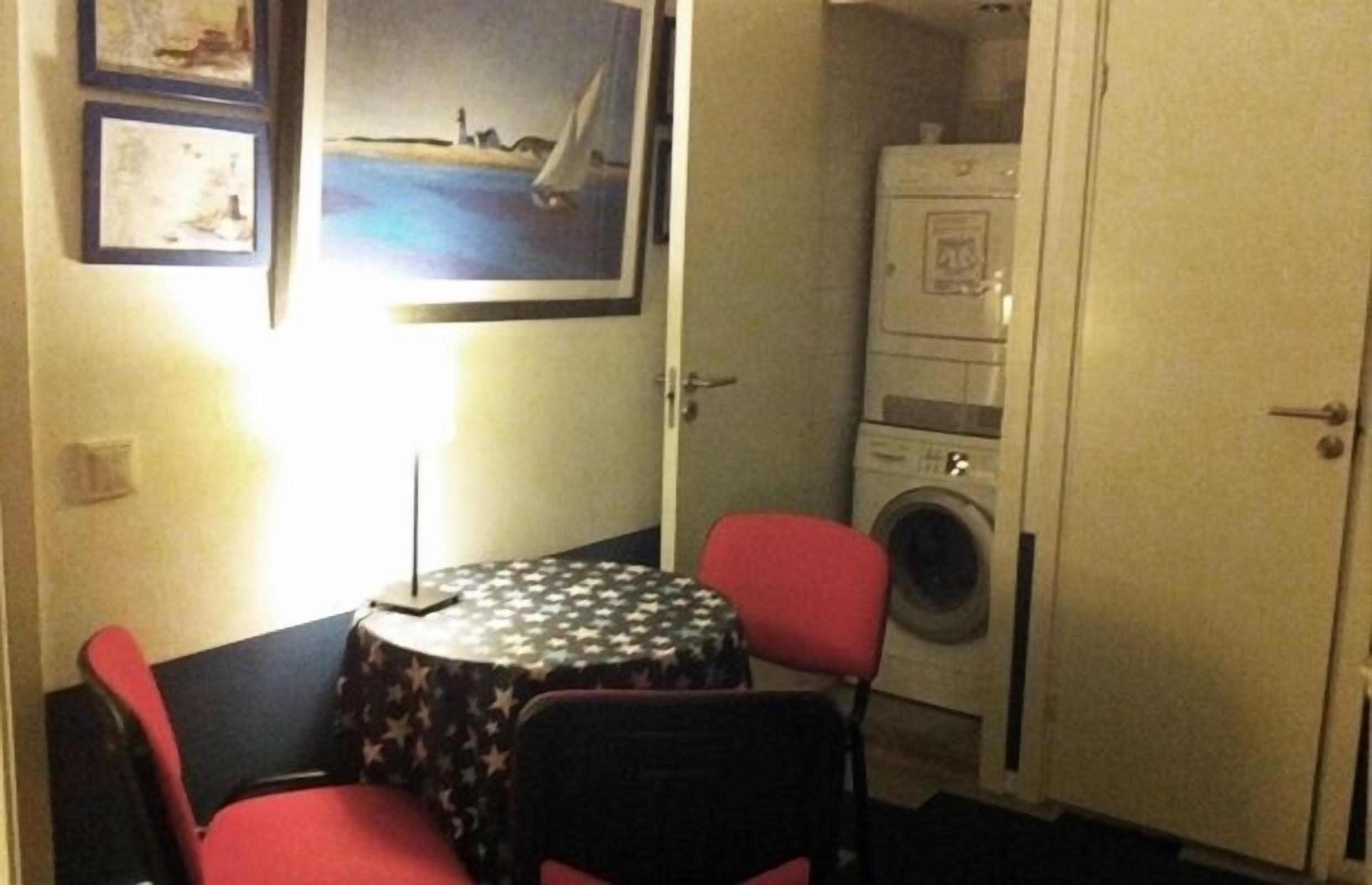 Ett litet rum med ett bord och två stolar, en tvättmaskin och en dörr.