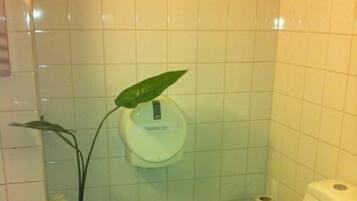 A bathroom with a toilet, a sink, and a plant.