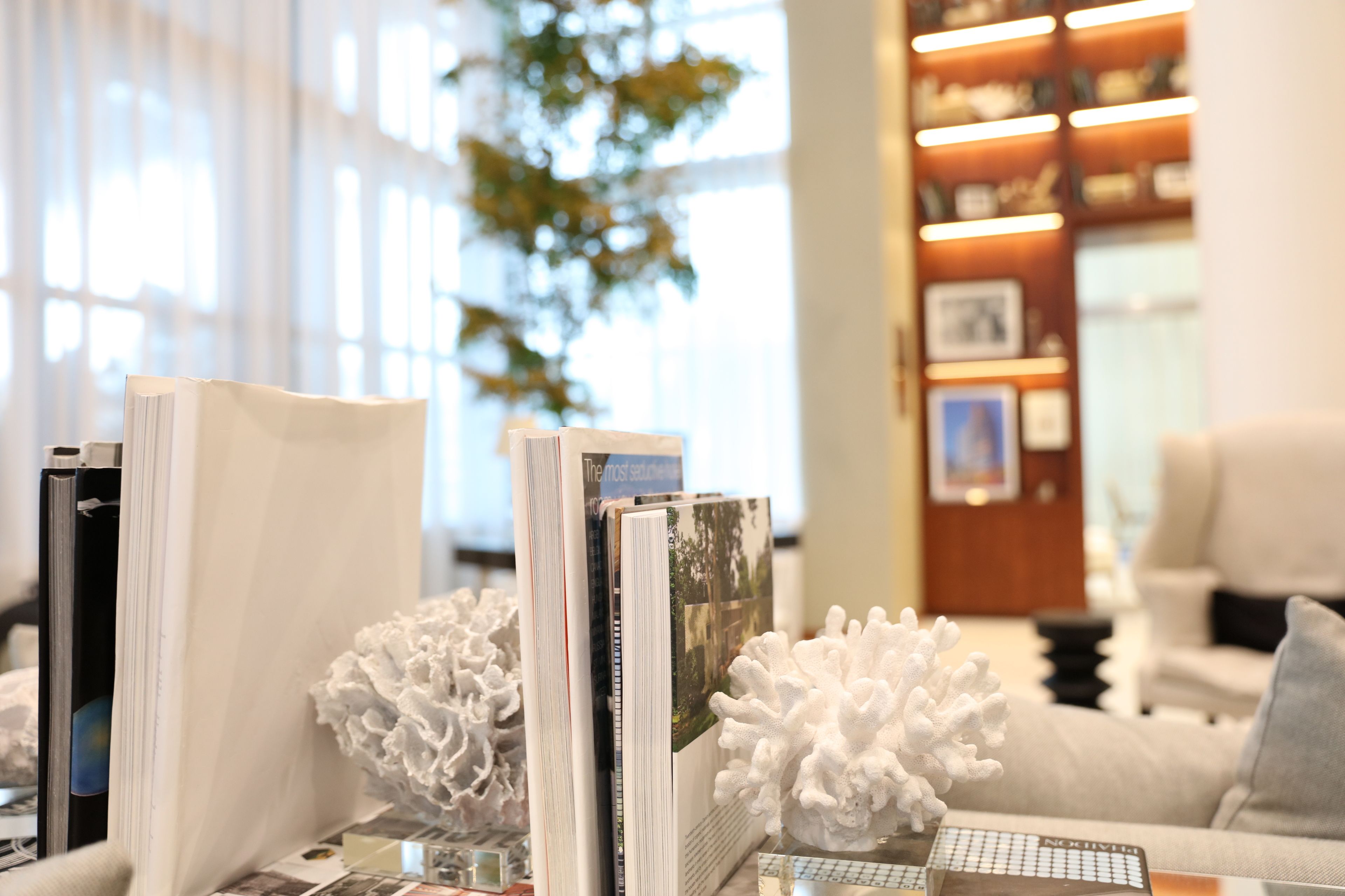 A well-lit room with a bookshelf, a white decorative piece, and a couch.