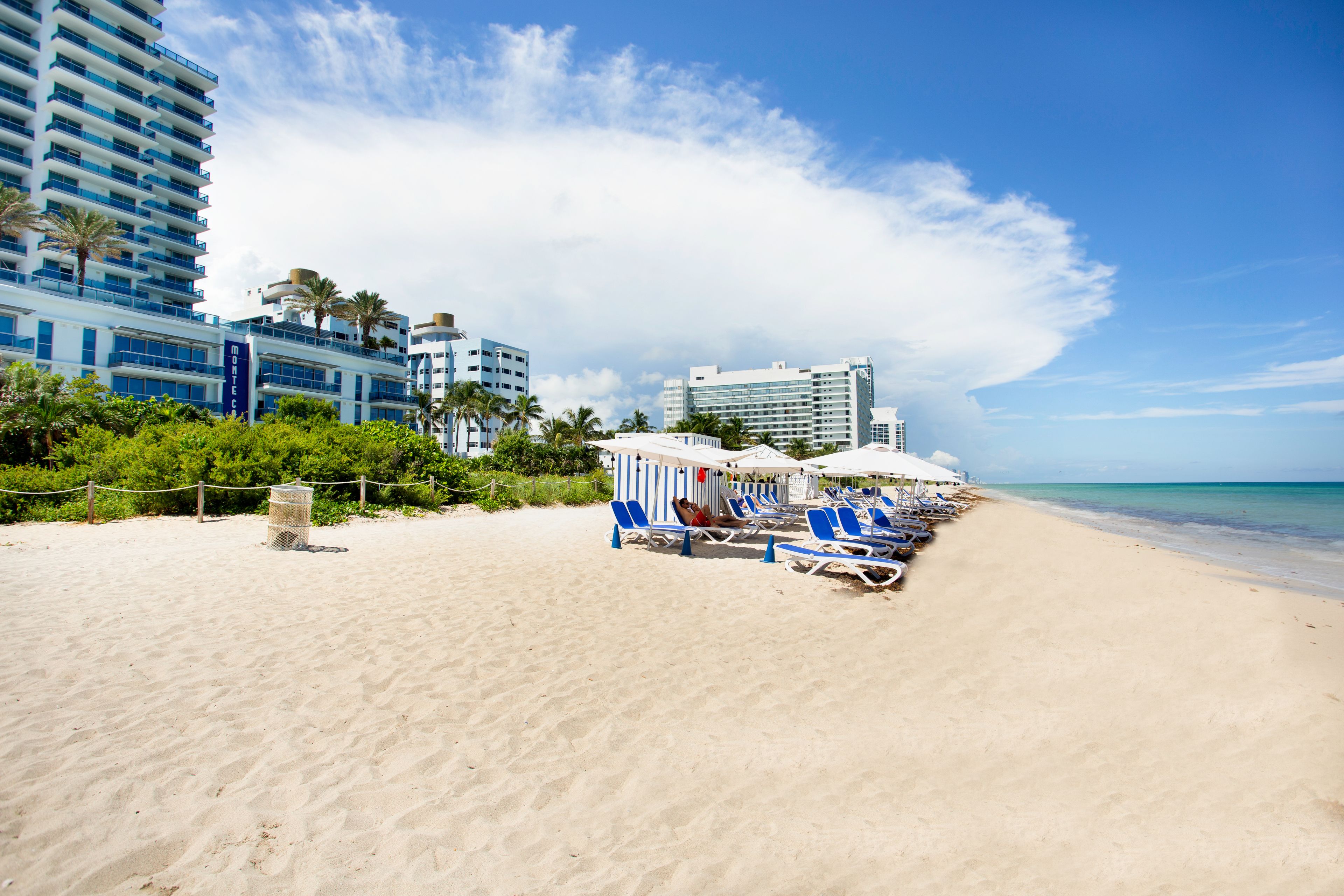 Na praia, areia branca, espreguiçadeiras, guarda-sóis 