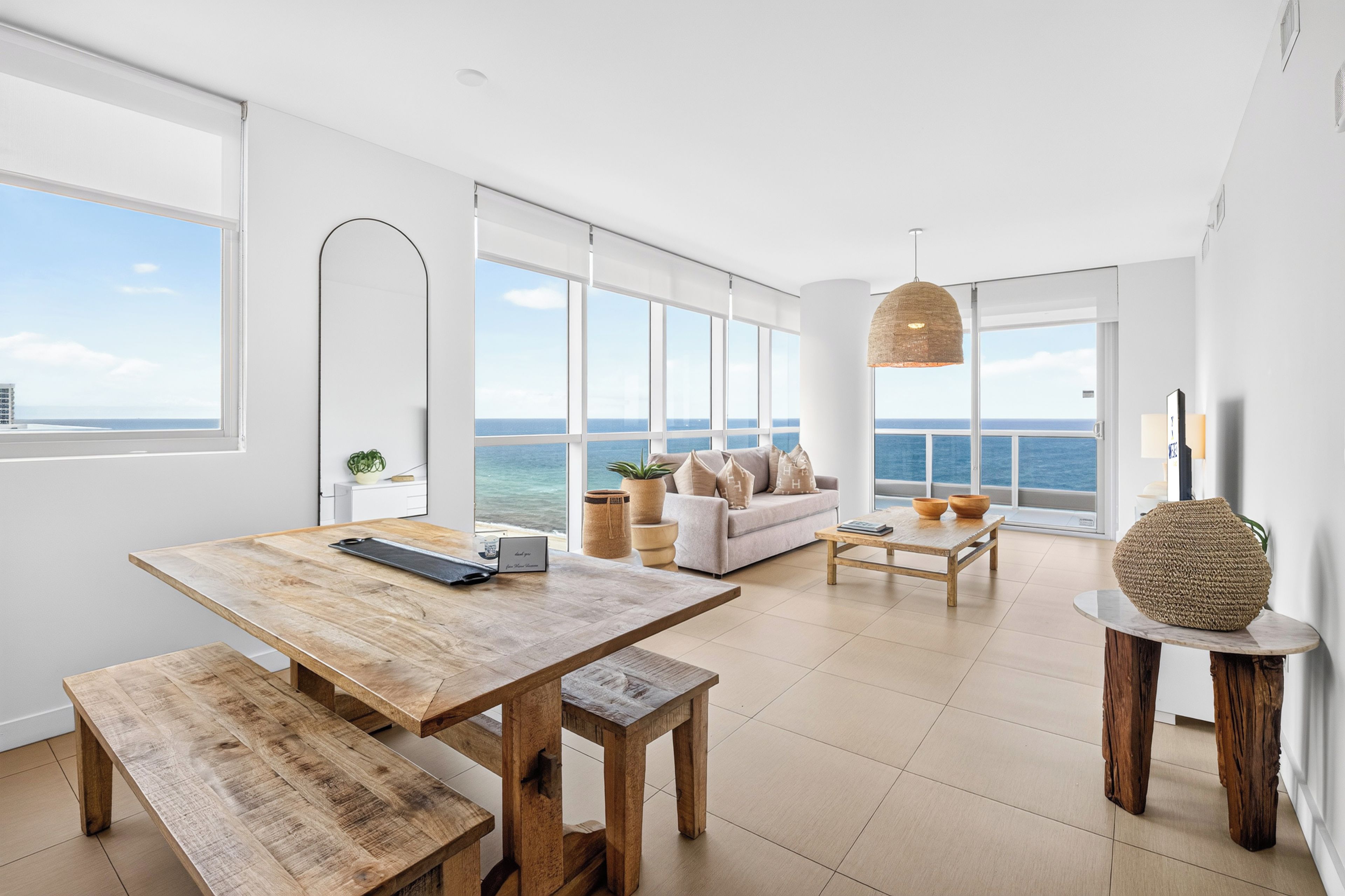 Ein modernes Wohnzimmer mit einem Holzespeisetisch, einer Couch und Blick aufs Meer.