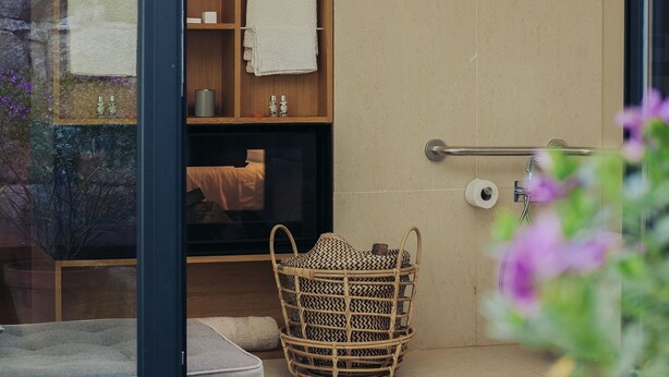 A bathroom with a wooden vanity, a towel rack, a basket, and a shower area. - Rosa Et Al Townhouse (Porto)