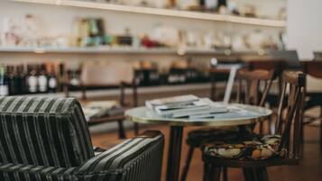 A cozy seating area with striped chairs and a round table, shelves with various items in the background.