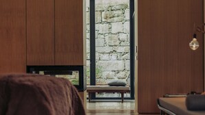 A modern bedroom with a stone wall, wooden floor, and a bed with a brown blanket. - Rosa Et Al Townhouse (Porto)