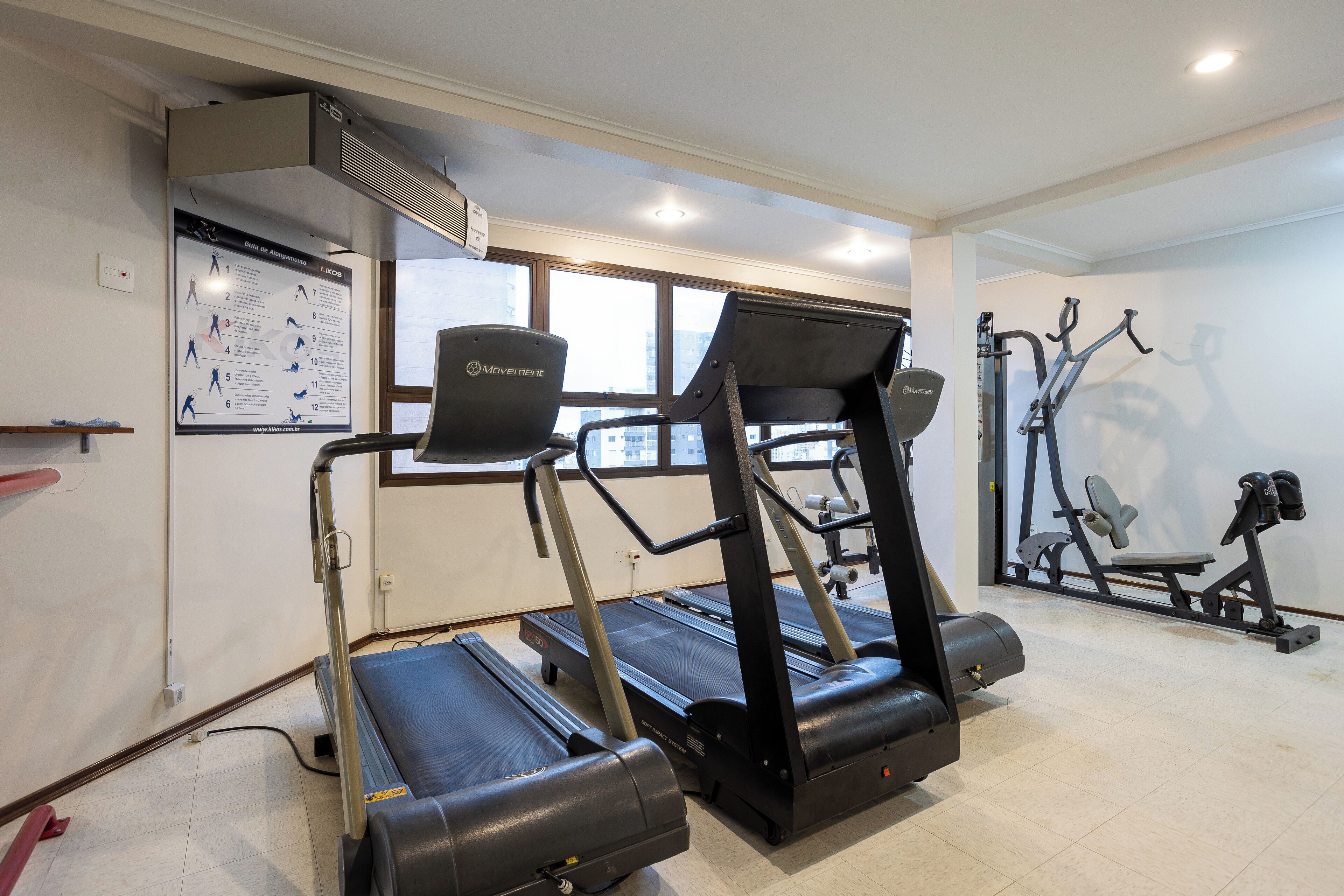 Ett gym med löpband, crosstrainers och en affisch på väggen.