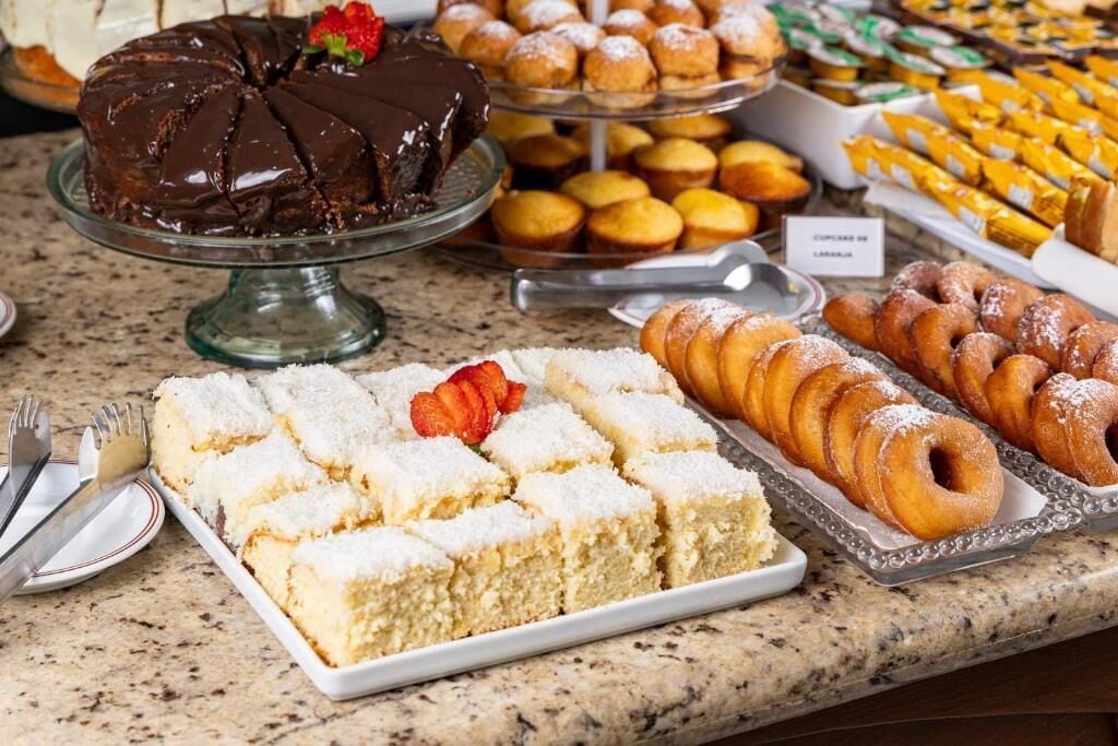 Un bufé con diversos postres, incluyendo un pastel de chocolate, pastelería y una bandeja de barras de limón.