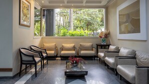 A modern waiting area with leather sofas, a coffee table, and framed artwork on the walls. - Park Tower Campinas Residence by Nacional Inn (Campinas)