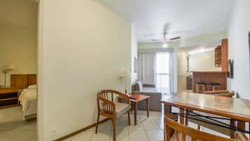 A hotel room with a dining area, a bed, a sofa, and a kitchenette.