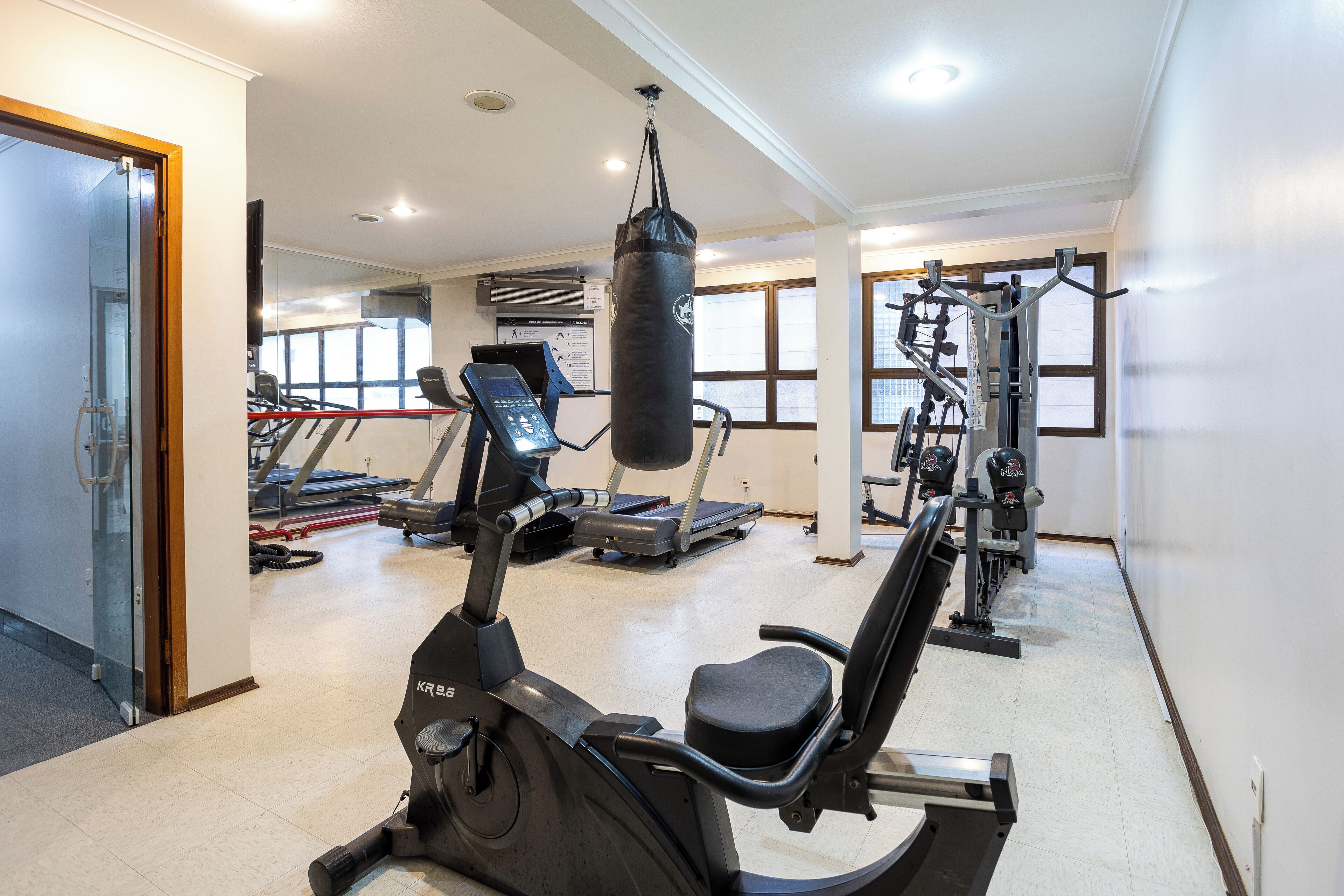 Ein Fitnessstudio mit Trainingsgeräten, darunter ein Crosstrainer, ein Sandsack und Gewichtsmaschinen.