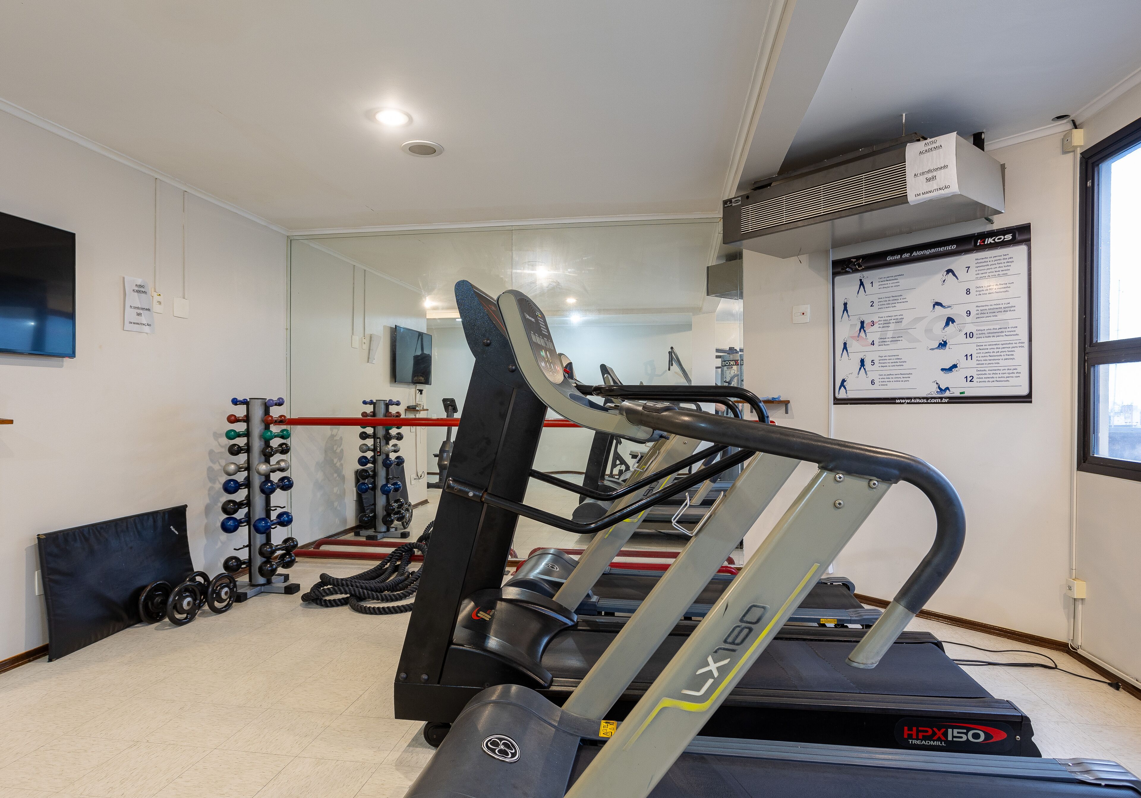 A gym with treadmills, weight machines, and a mirrored wall.