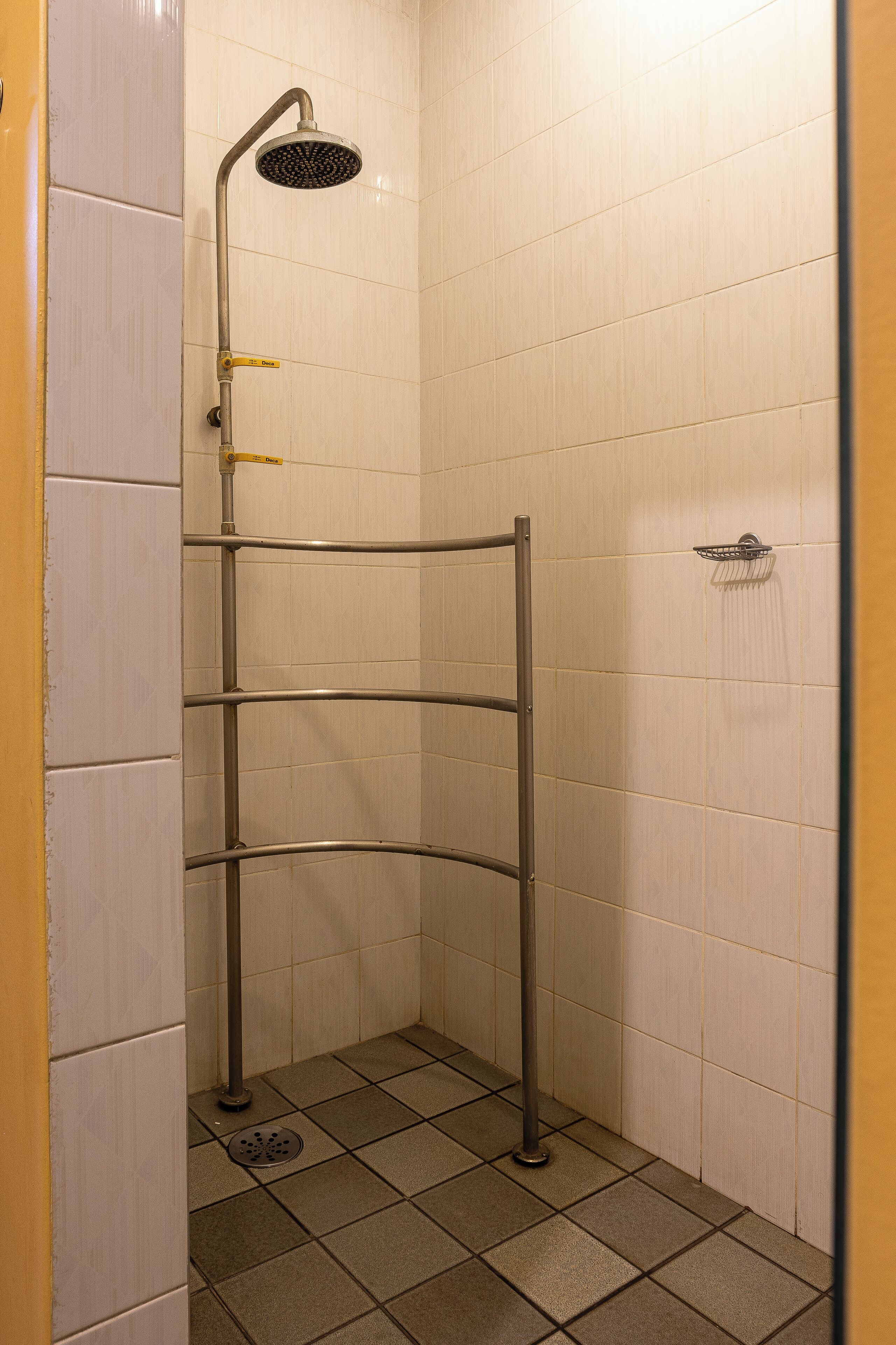 A shower with a handheld showerhead and a wall-mounted faucet.