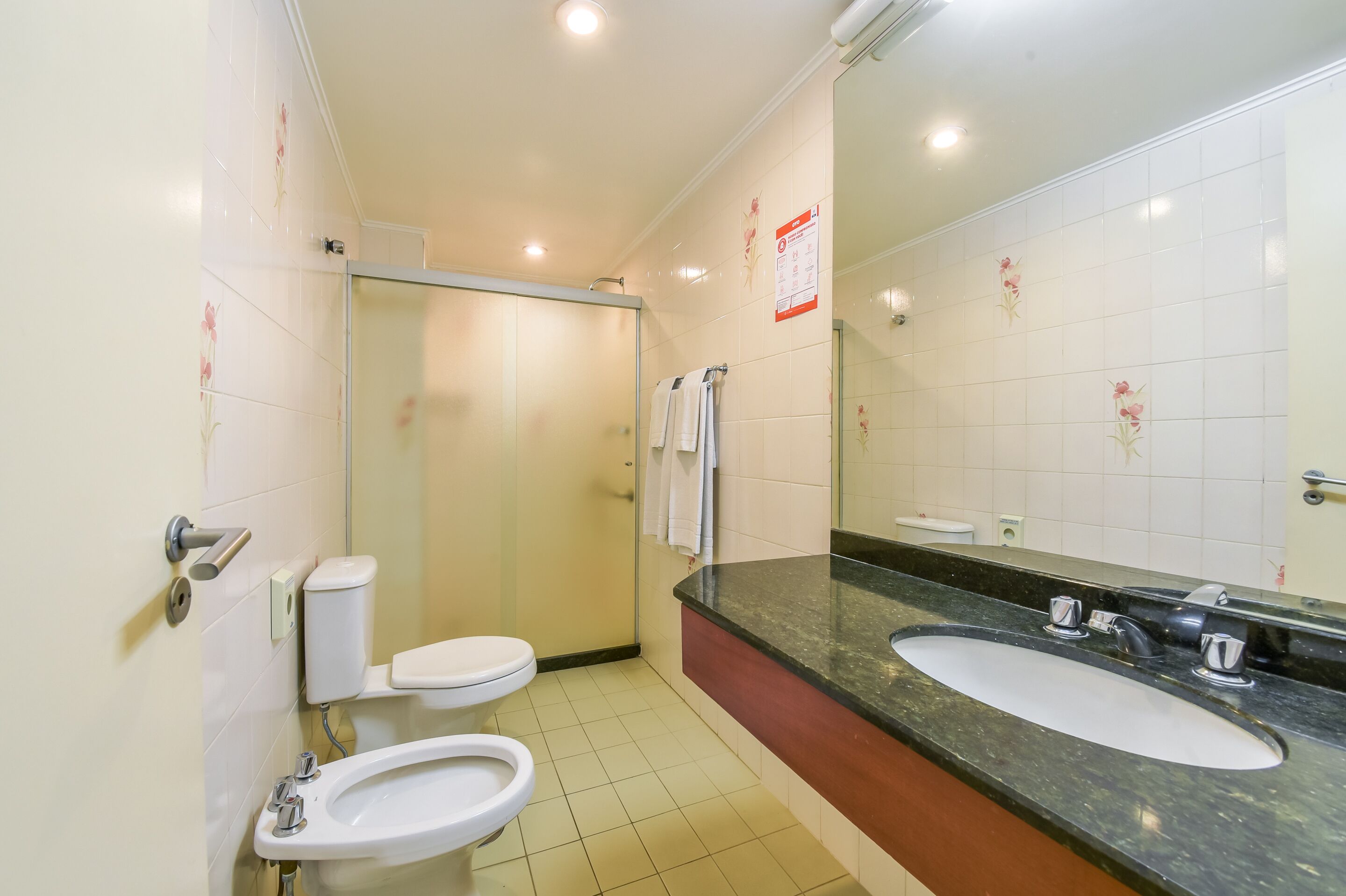 Un baño con inodoro, bidé, lavabo y cabina de ducha de vidrio.