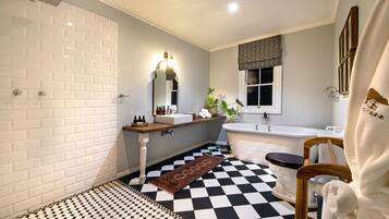A bathroom with a checkered floor, a white bathtub, a wooden vanity, and a mirror with lights.