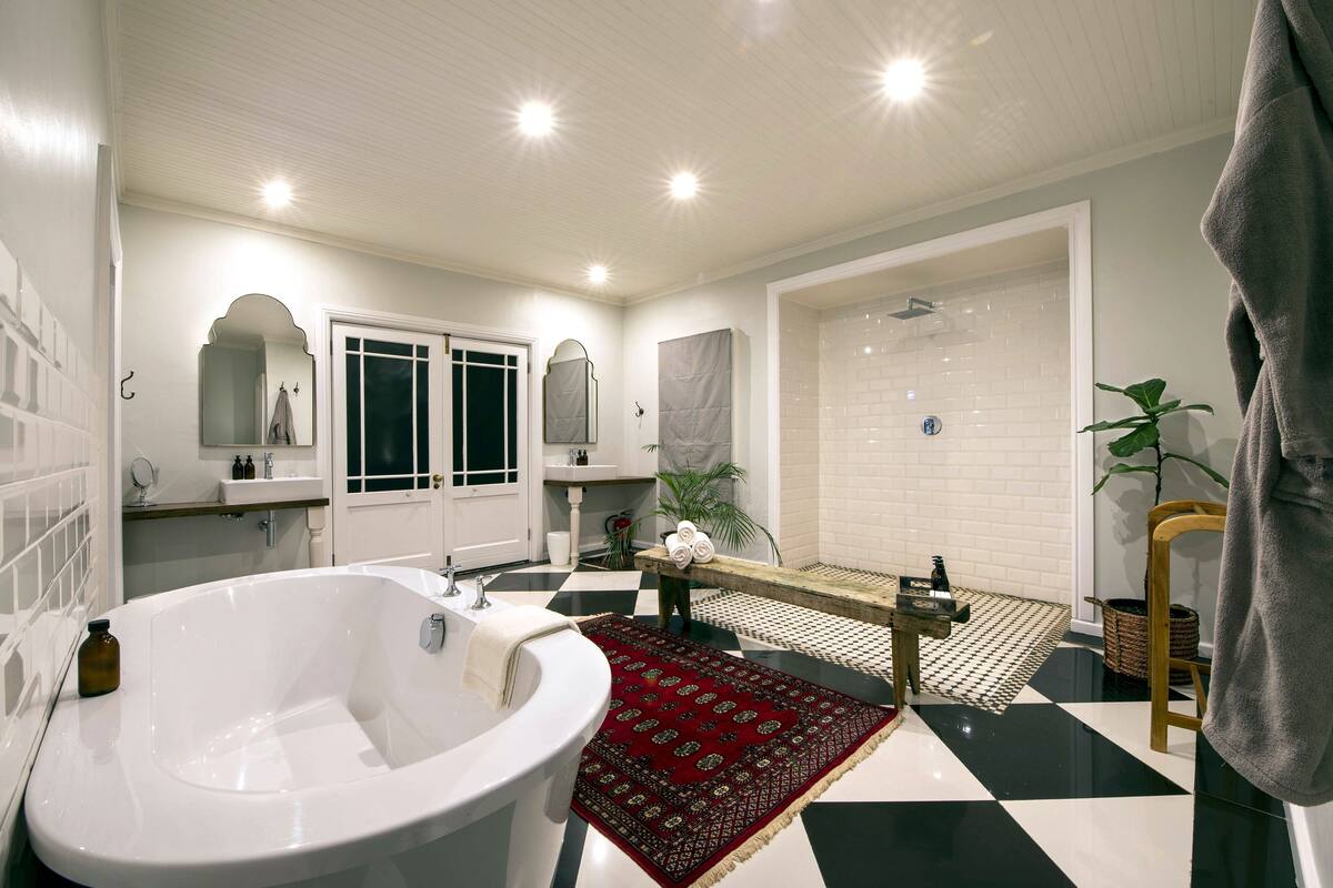 A modern bathroom with a large bathtub, a separate shower area, and a vanity with a mirror.