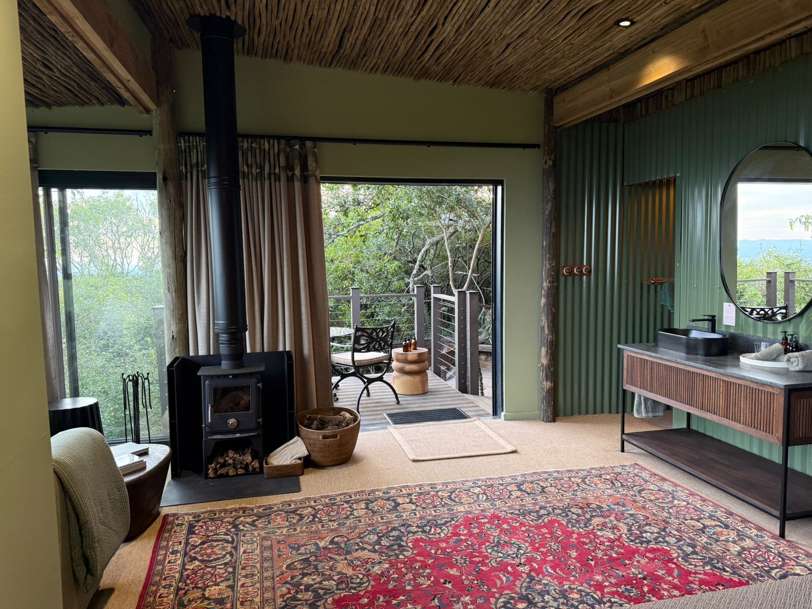 A cozy room with a wood-burning stove, a large rug, and a view of the outdoors.