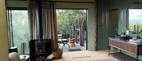 A cozy room with a wood-burning stove, a large rug, and a view of the outdoors.