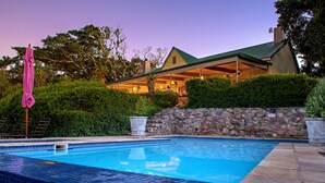 Une piscine avec des murs en pierre et une terrasse carrelée.