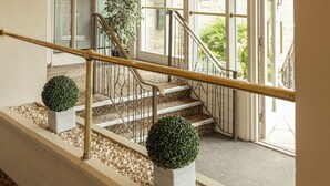 A staircase with a white railing, leading to a door with glass panels. - The Gibside Hotel (Newcastle-upon-Tyne)