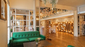 A green sofa and a table in a well-lit room with wooden flooring and a decorative ceiling. - The Gibside Hotel (Newcastle-upon-Tyne)