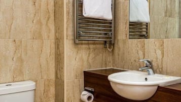 Ein Badezimmer mit Marmorwand, Toilette, Waschbecken mit Spiegel und Handtuchhalter.