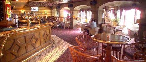 A bar area with a counter, chairs, and a television screen.