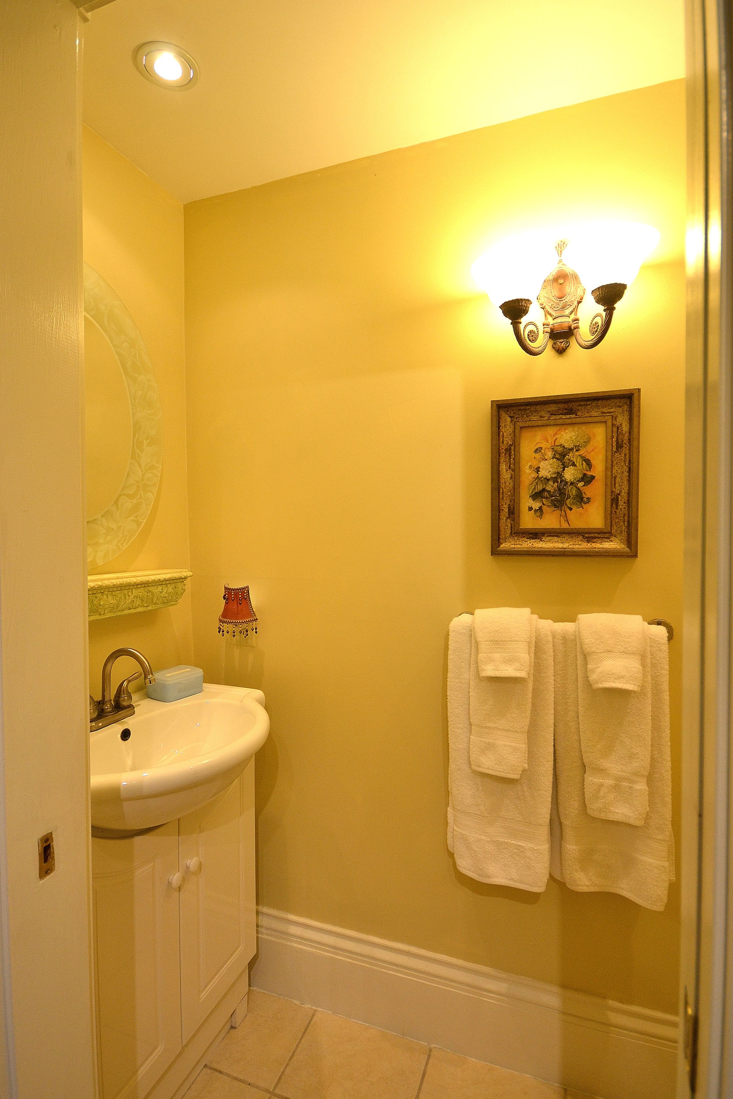 A bathroom with a sink, mirror, and two towels hanging on the wall.