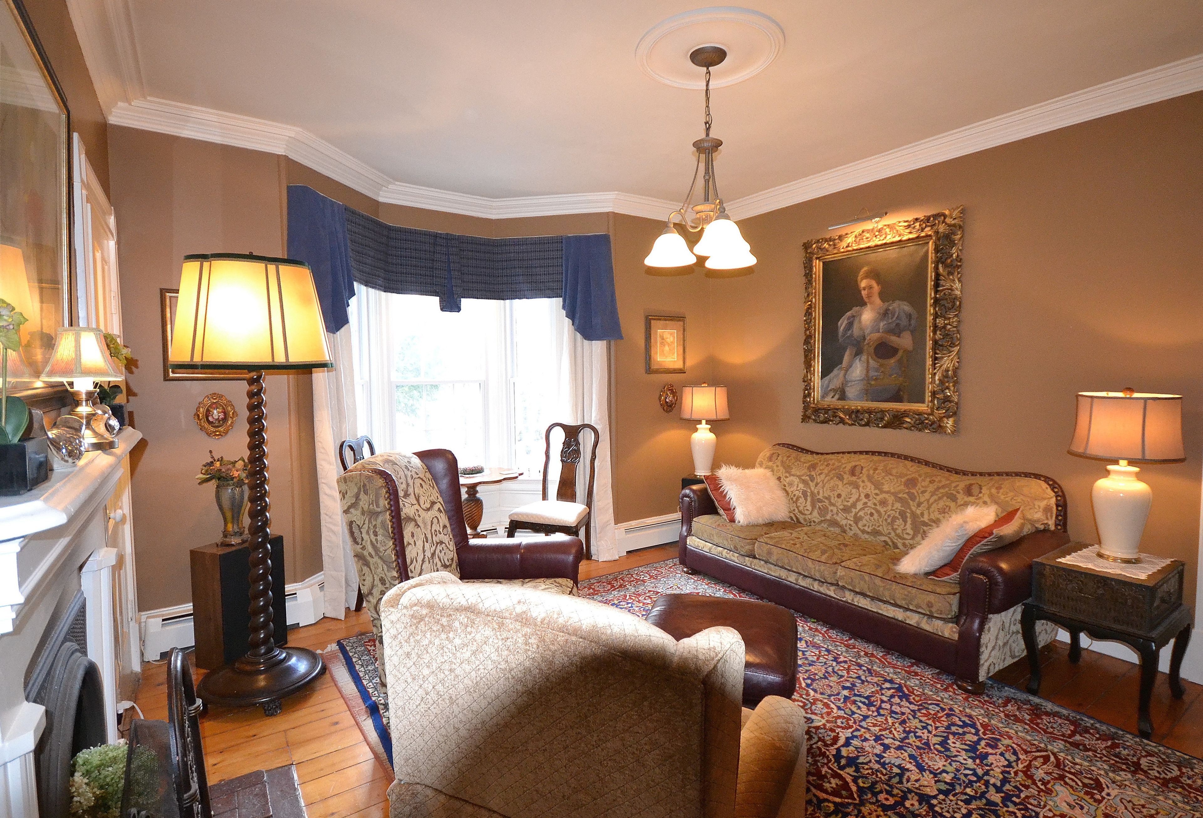 A traditional living room with a sofa, armchairs, a patterned rug, and a fireplace.