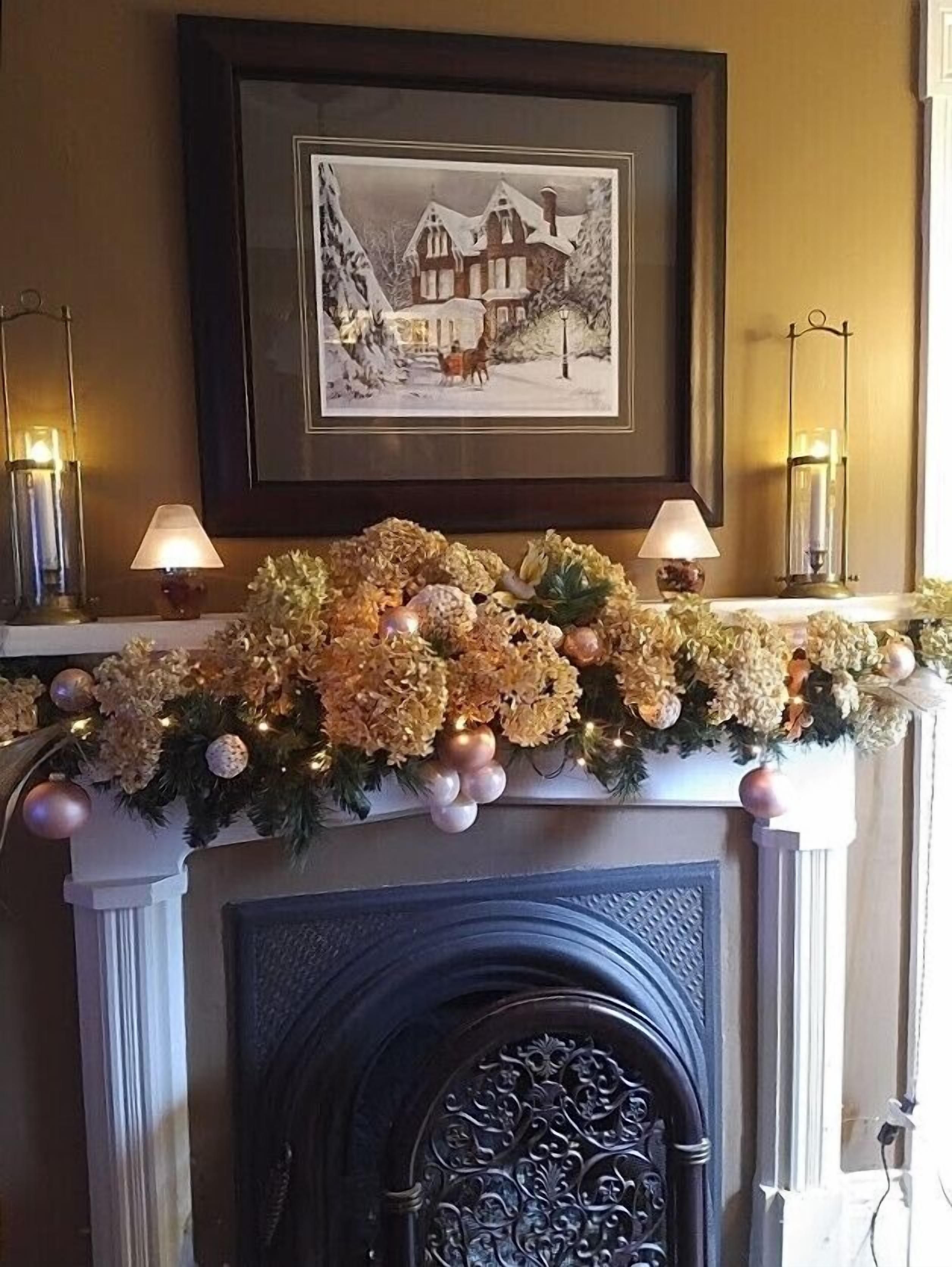 A fireplace with a decorative garland and two wall-mounted lamps.