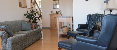 Ein Wohnzimmer mit grauem, gemustertem Sofa, einem blauen Ledersessel und einem Holztisch.