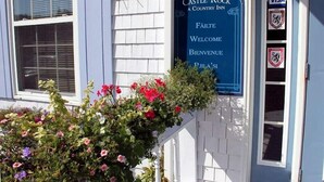 Een blauw bord met 'Castle Rock Country Inn' en 'Welkom' in verschillende talen.